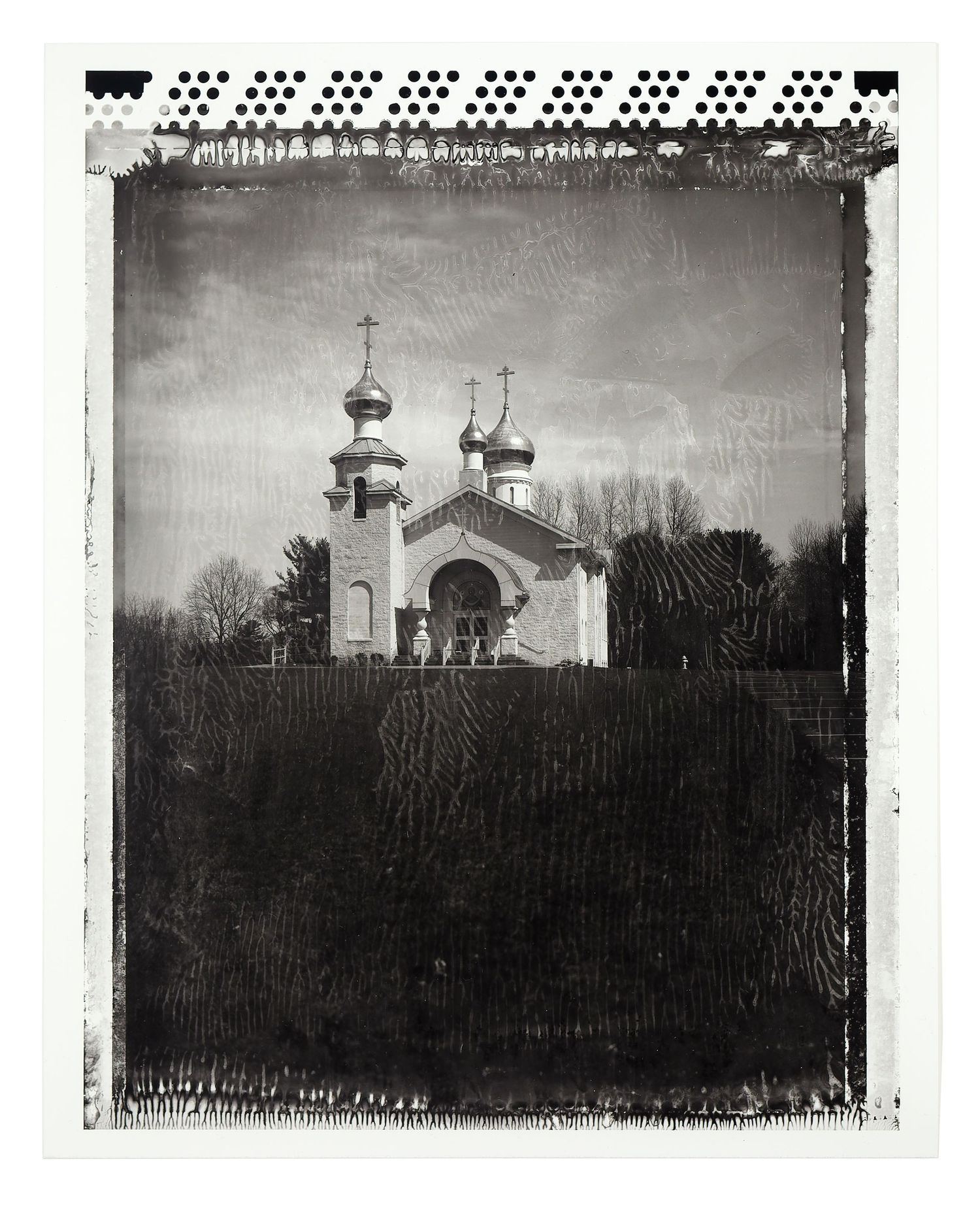 Black and white photo of a Russian Orthodox church with onion domes on a hill.
