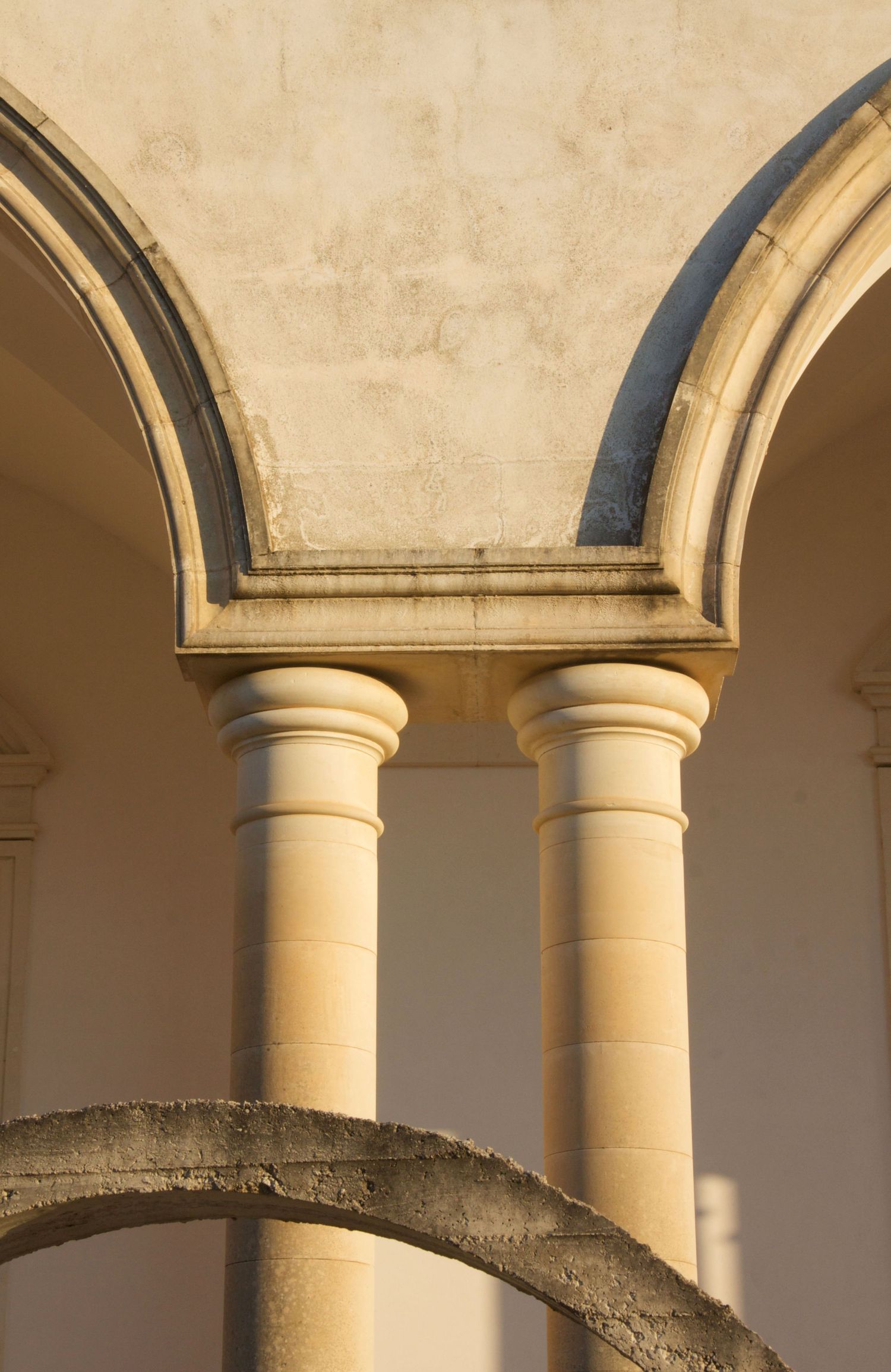 Classic stone columns supporting double arches in warm golden sunlight at a historic Mediterranean cloister.