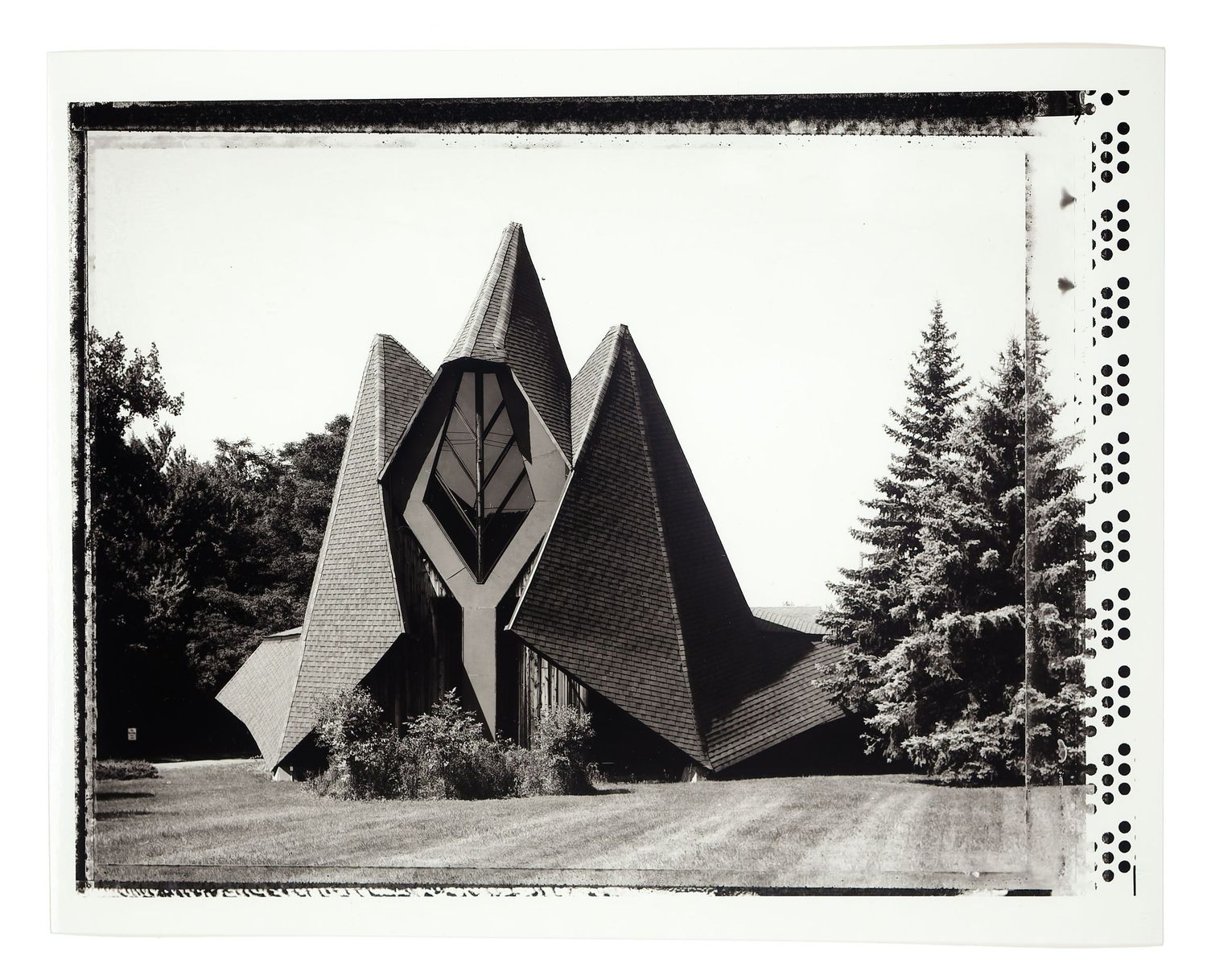 Black and white photo of a modern angular church with dramatic triangular architecture and tall spires.