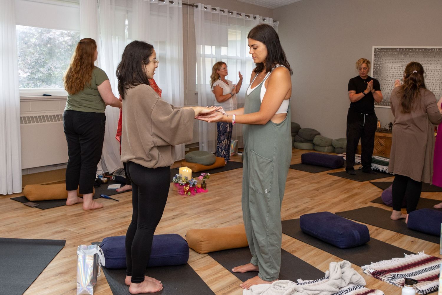 Women practice mindfulness exercises on yoga mats in a bright, serene wellness studio setting.