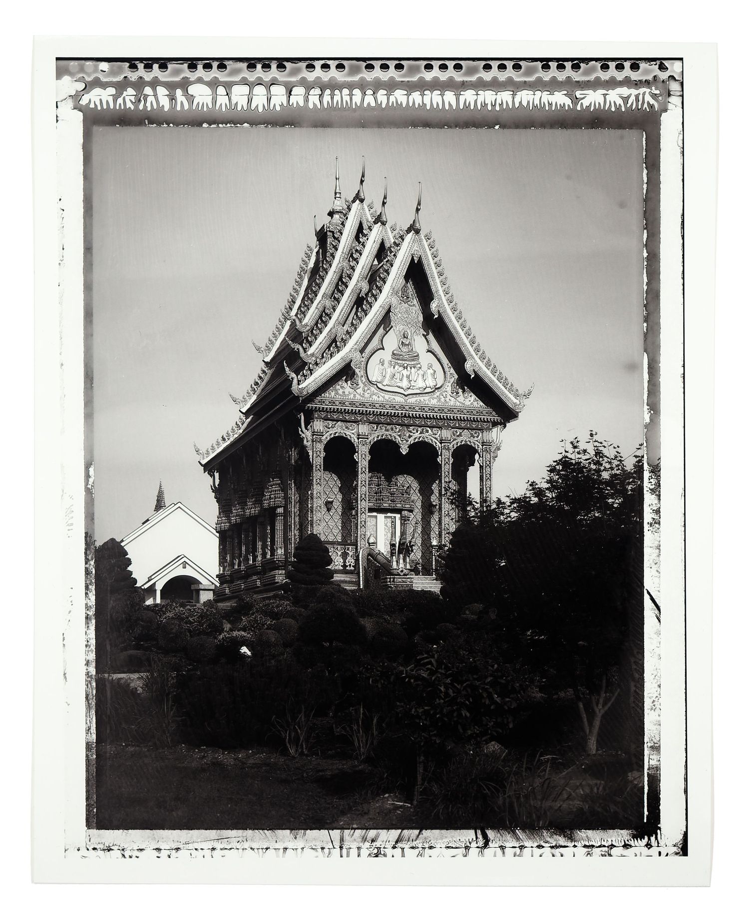 Black and white photo of an ornate Thai Buddhist temple with tiered roof and decorative facade.