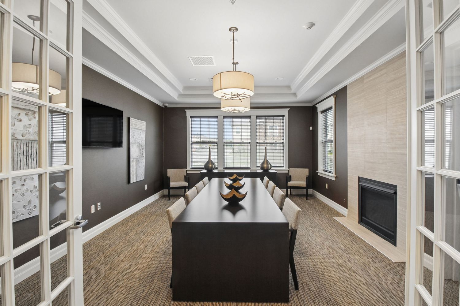 Sophisticated conference room with dark walls, long table, pendant light, and French doors.