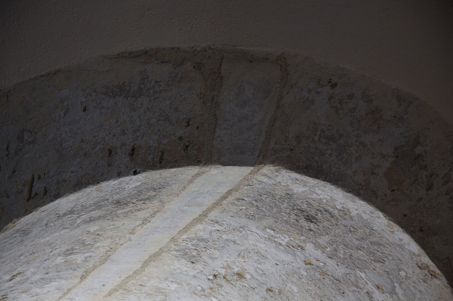 Close-up of a weathered stone arch with rough texture and a subtle white stripe detail.
