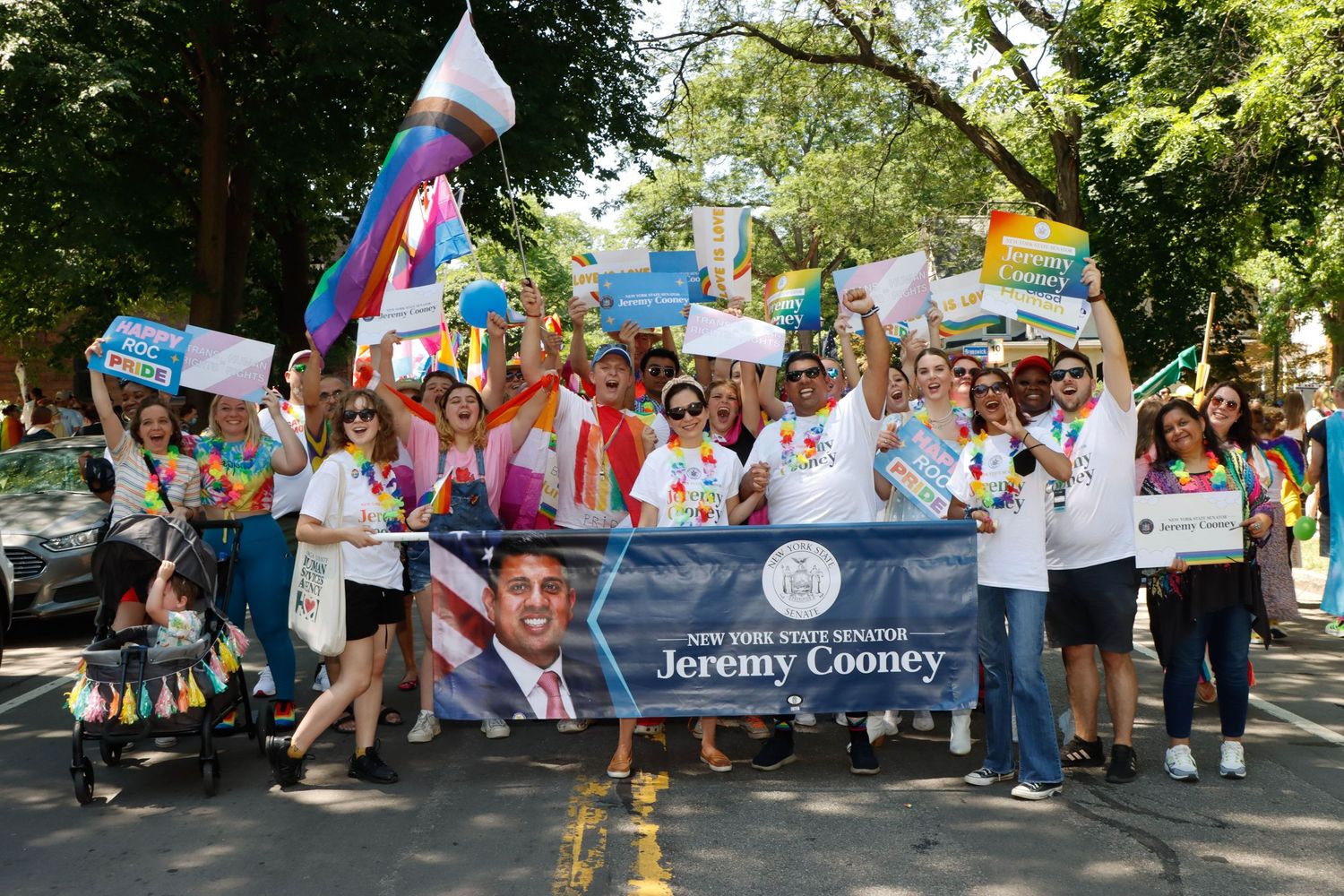 Crowd marching in Pride parade holding signs for NY State Senator Jeremy Cooney.