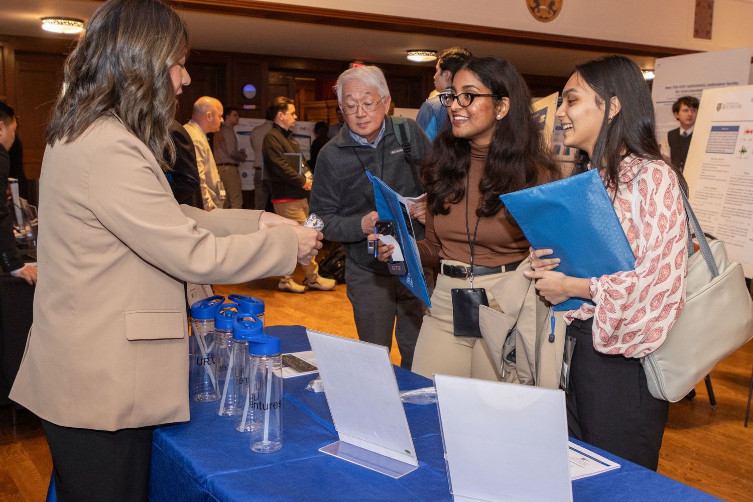 Students shaking hands with a professional recruiter at an academic career networking fair.