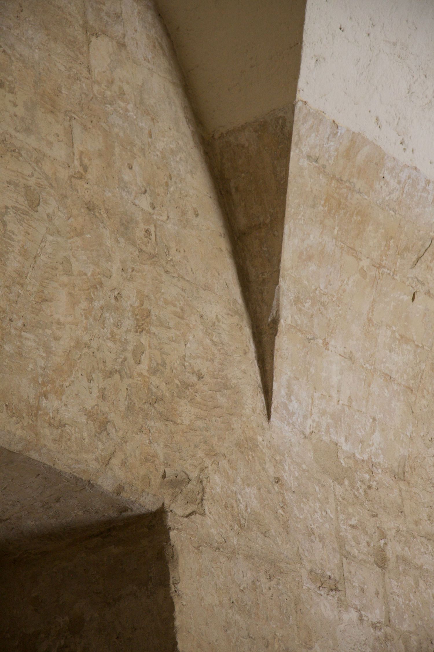 Abstract architectural detail of intersecting limestone stone walls forming sharp triangular shadow in ancient historic structure.