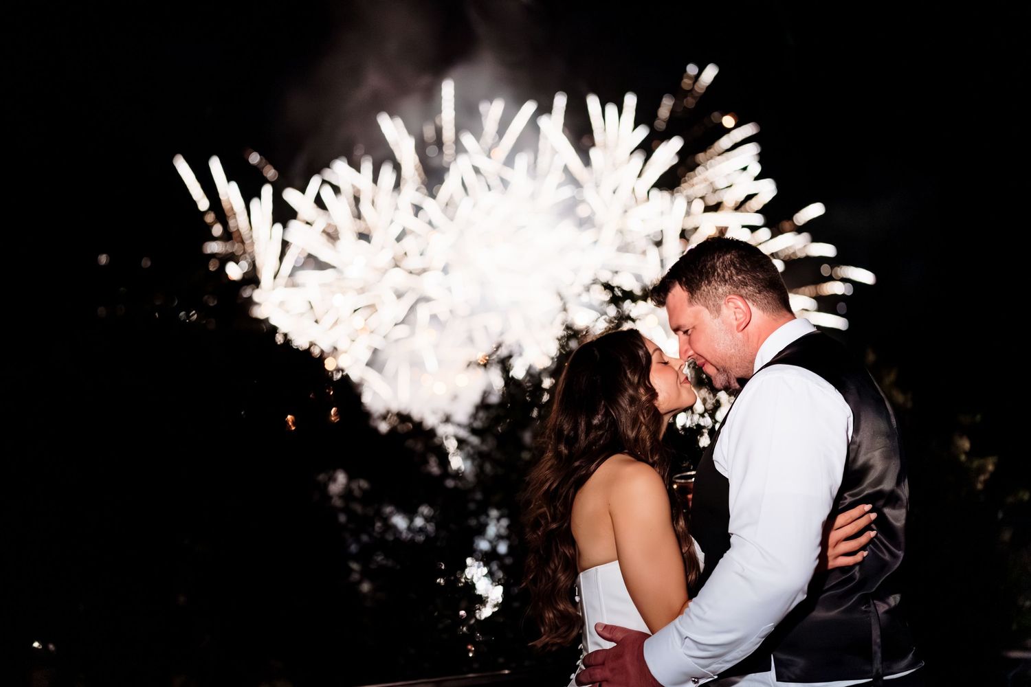 A couple shares a romantic dance under a shower of white sparklers at their wedding reception.