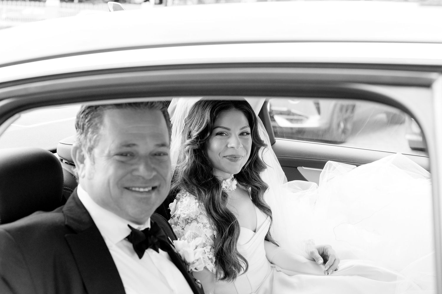 A happy couple sits together in the backseat of a vintage car as they celebrate their wedding day.