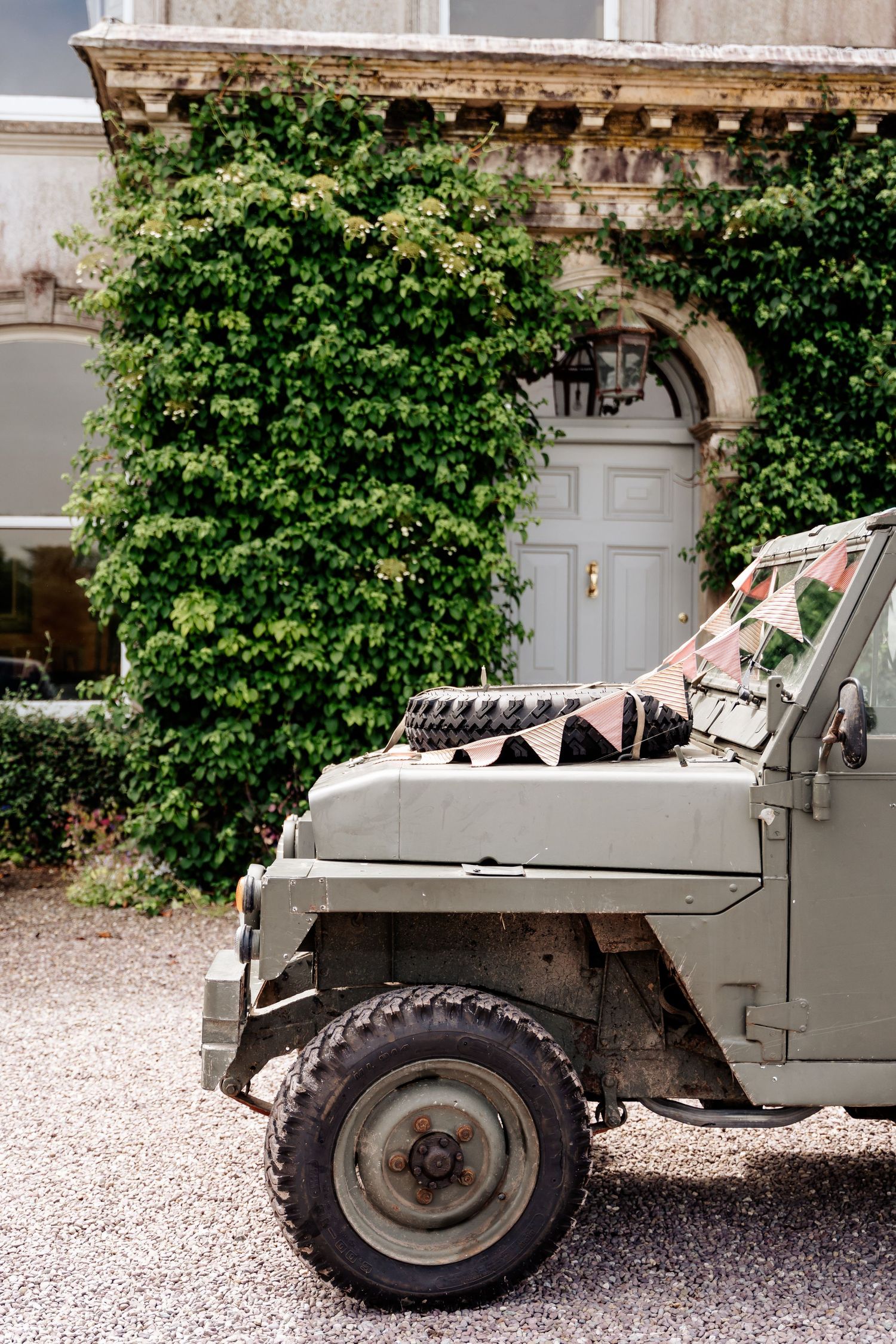 Vintage military jeep detail with ivy-covered doorway in the background.