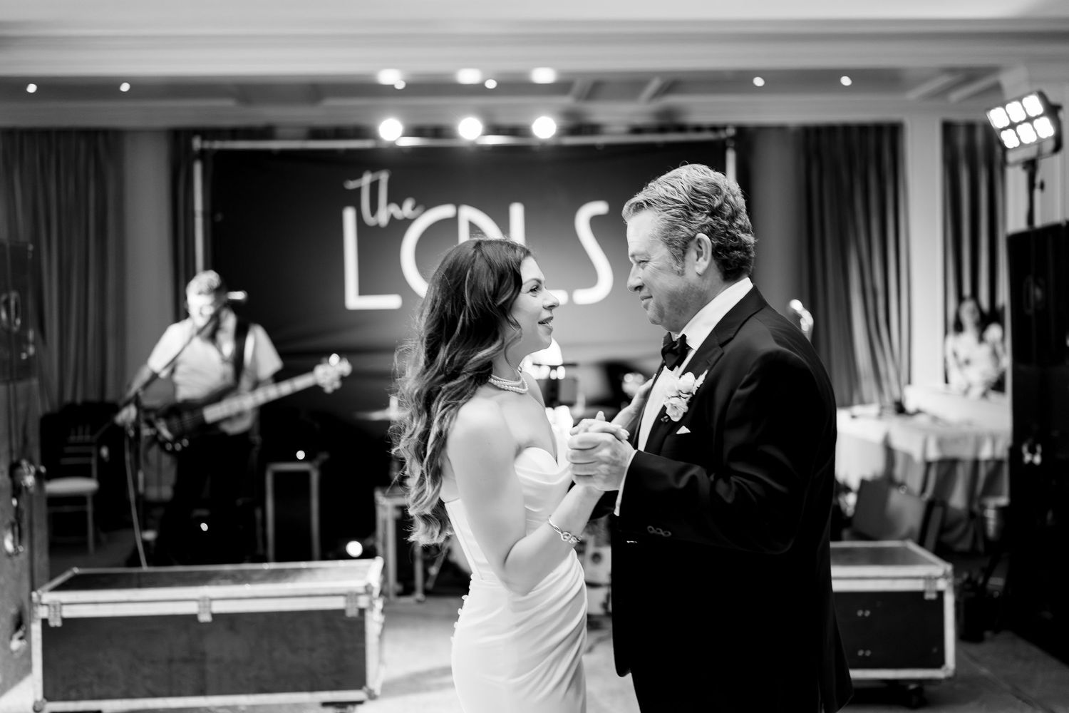 A couple shares their first dance at their wedding reception while guests look on at the elegant venue.