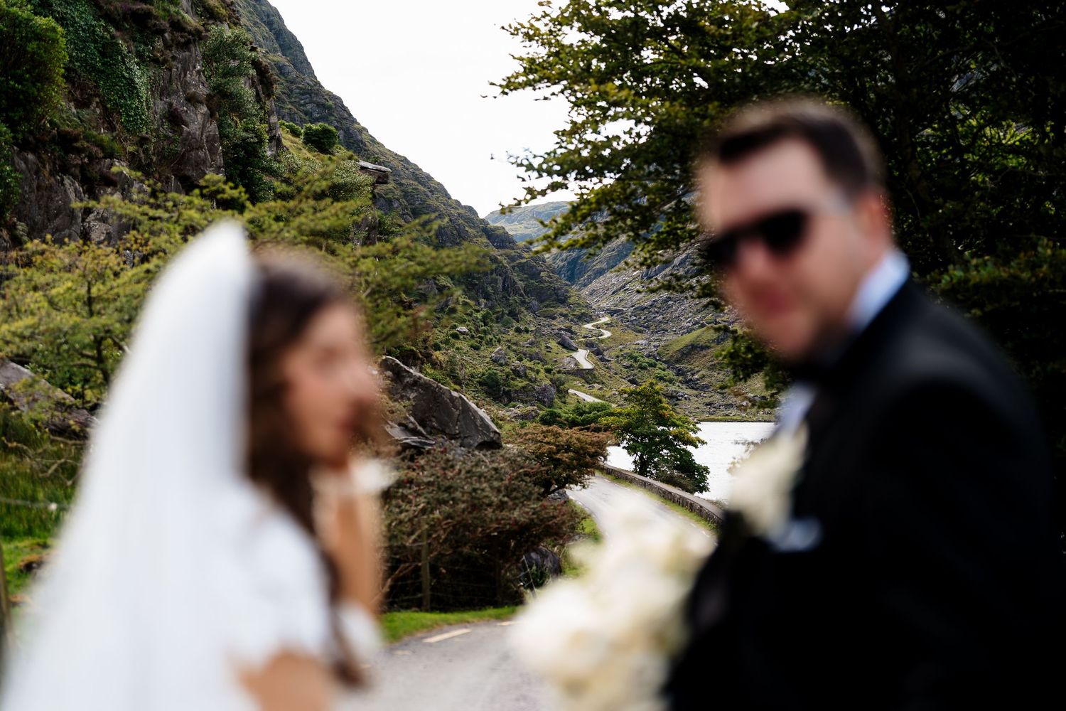 A couple in wedding attire embraces in front of scenic mountain landscapes and natural scenery.