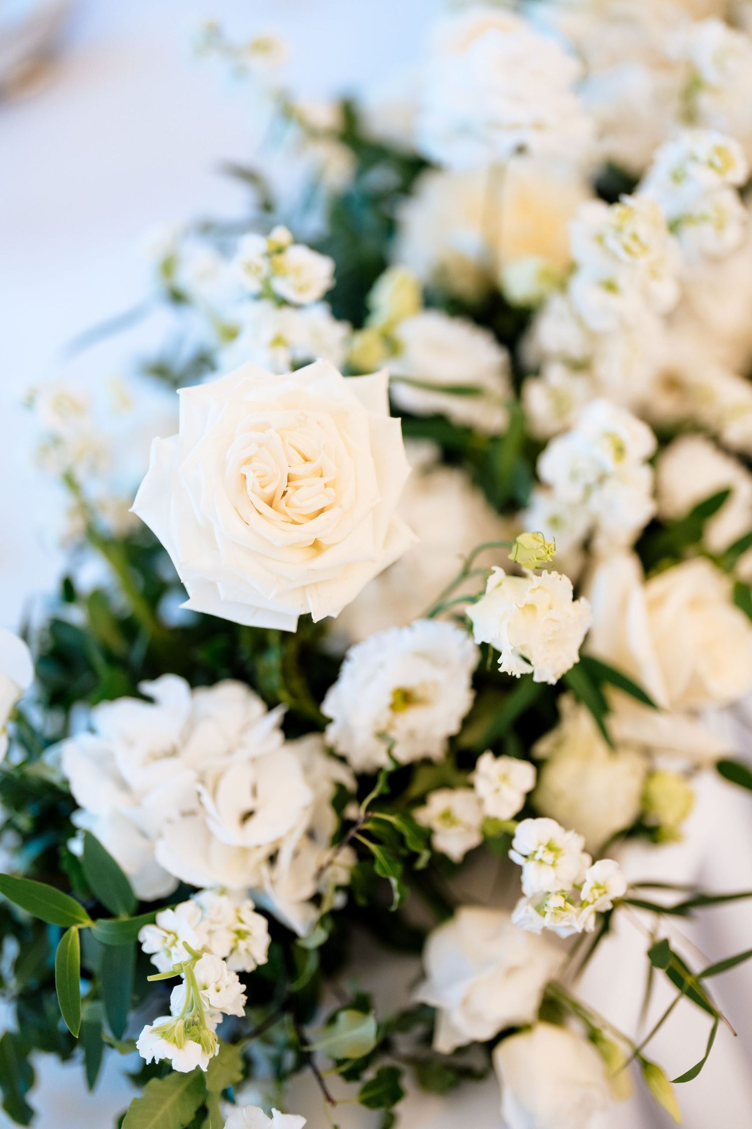A close-up view of delicate white roses and small flowers arranged together in soft lighting.