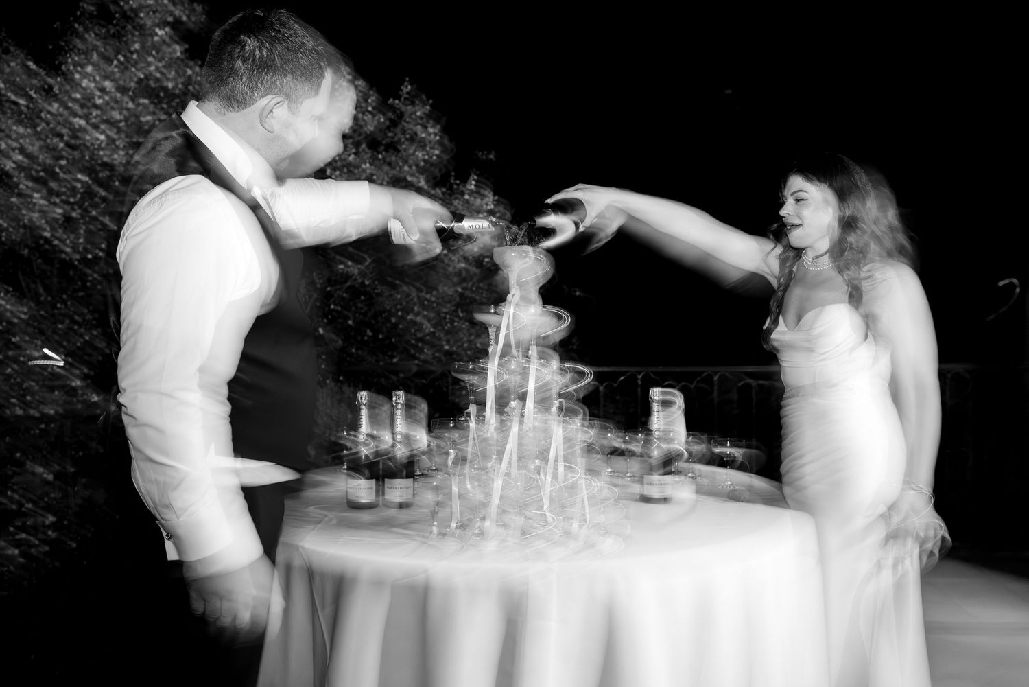 Hands pouring champagne into a delicate tower of stacked crystal glasses for a special celebration event.