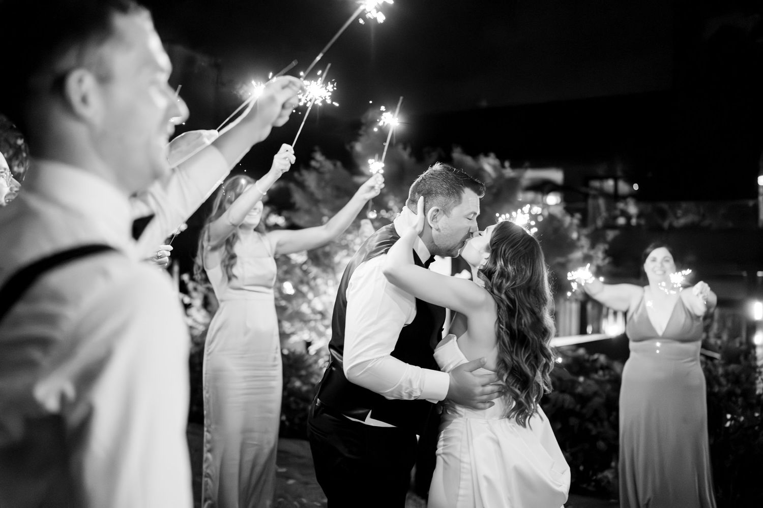 People dancing together in formal attire on a dimly lit dance floor at an elegant evening celebration.