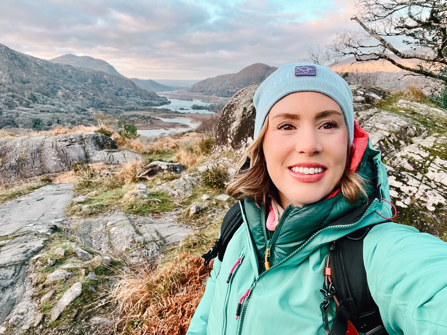 Selfie taken on a winter hiking trail overlooking lakes and mountains in Ireland's Killarney National Park at sunset.
