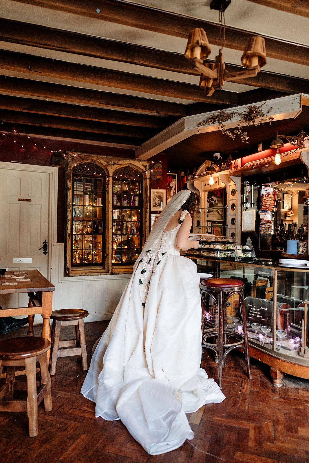 A series of ghost decorations hang from wooden ceiling beams in a rustic room with antique displays and warm lighting.