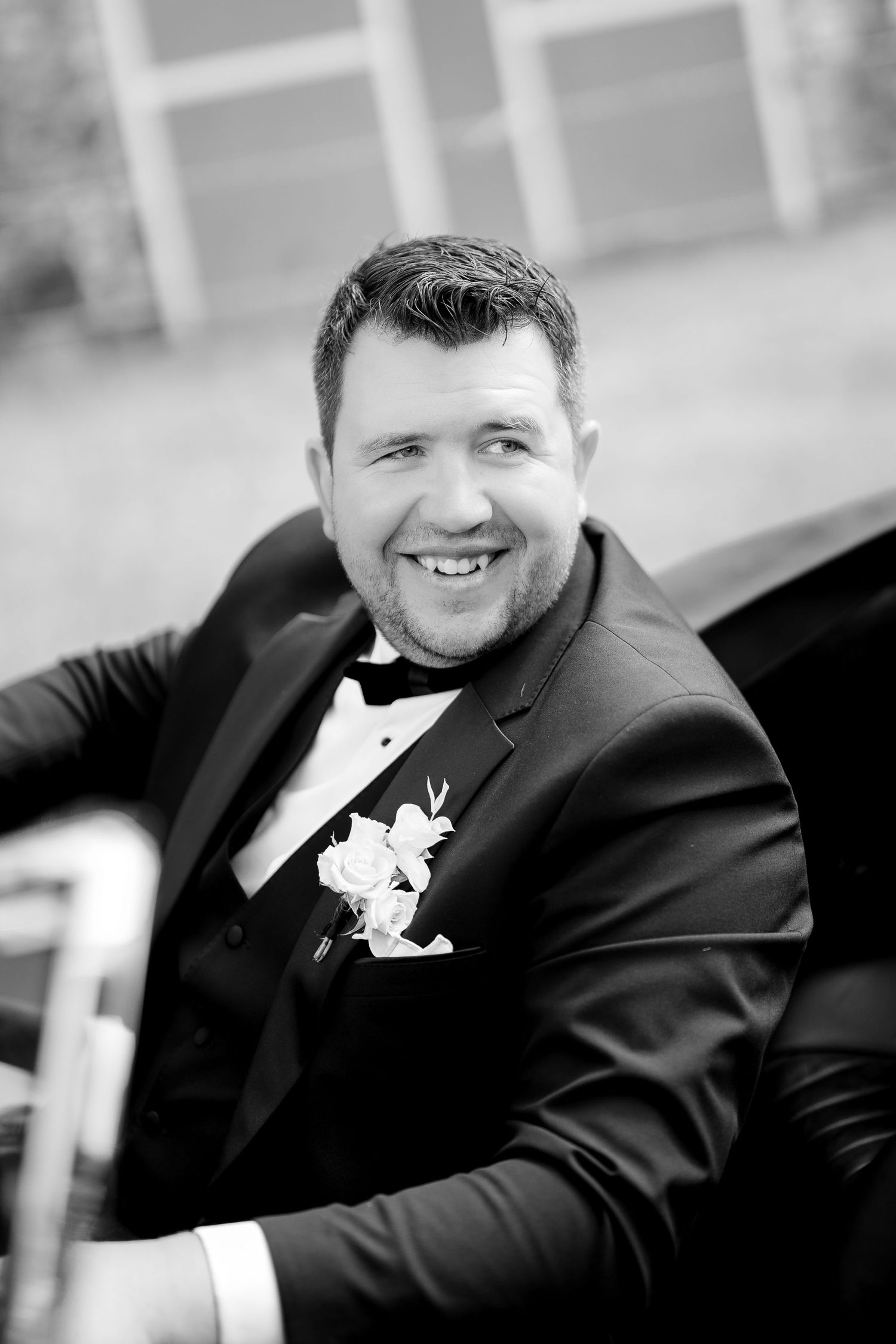 Four black and white portraits showing someone in a formal suit jacket with a boutonniere smiling at different angles.