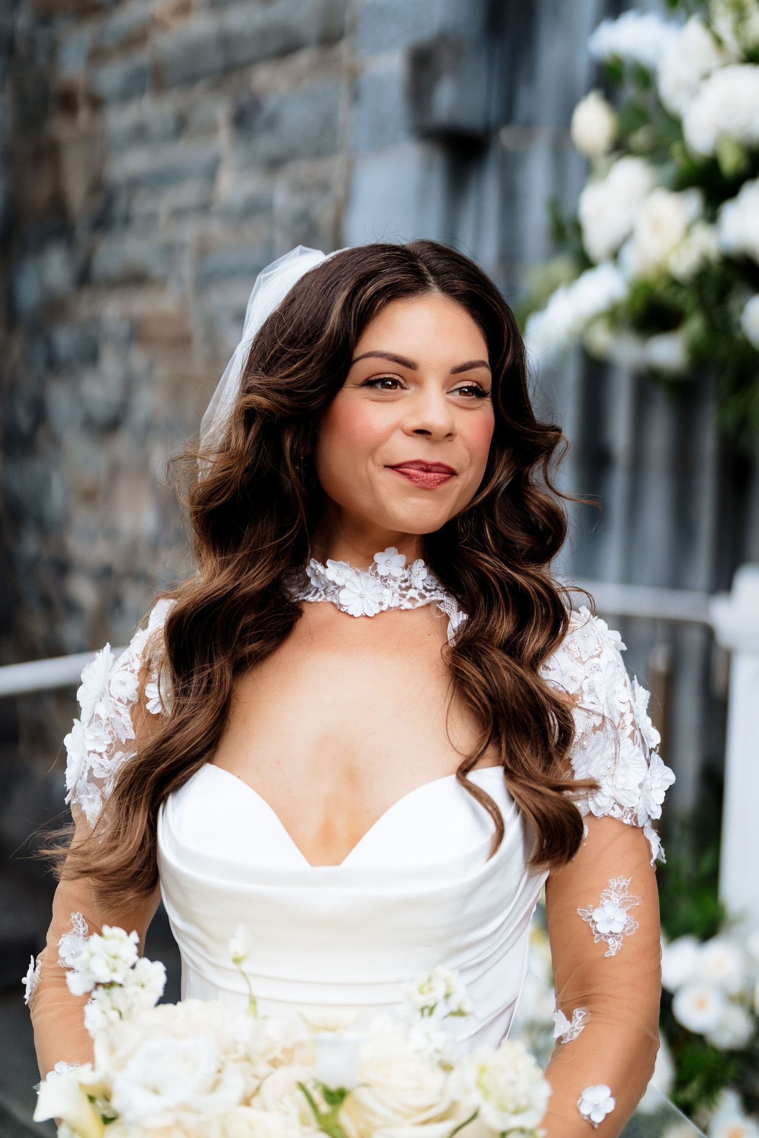 Four sequential photos of a bride in a white wedding dress with lace details and floral bouquet posing outside a stone building.