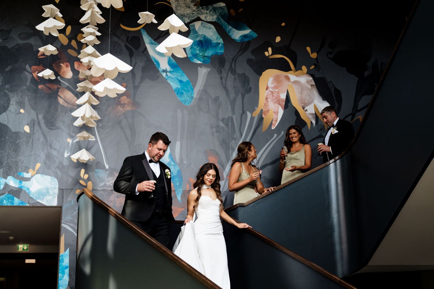 Origami-style white paper birds float delicately above a dance floor at what appears to be a wedding celebration.