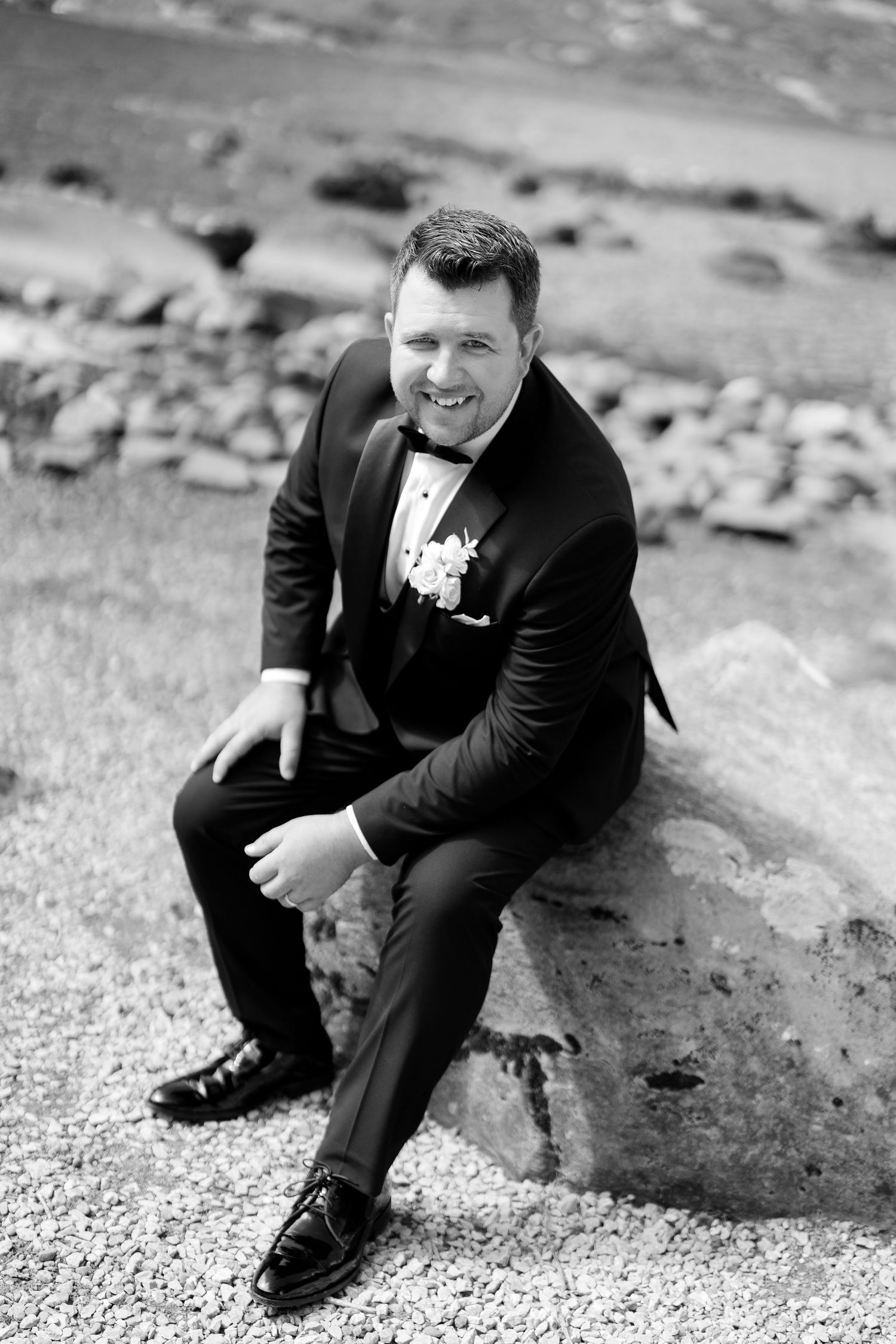 A black and white series of photos showing a person in a suit sitting casually on rocks outdoors.