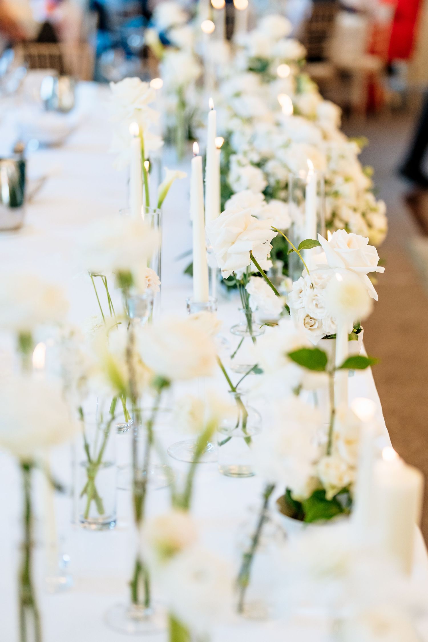 Elegant wedding reception table decorations featuring delicate white flowers in clear glass vases.