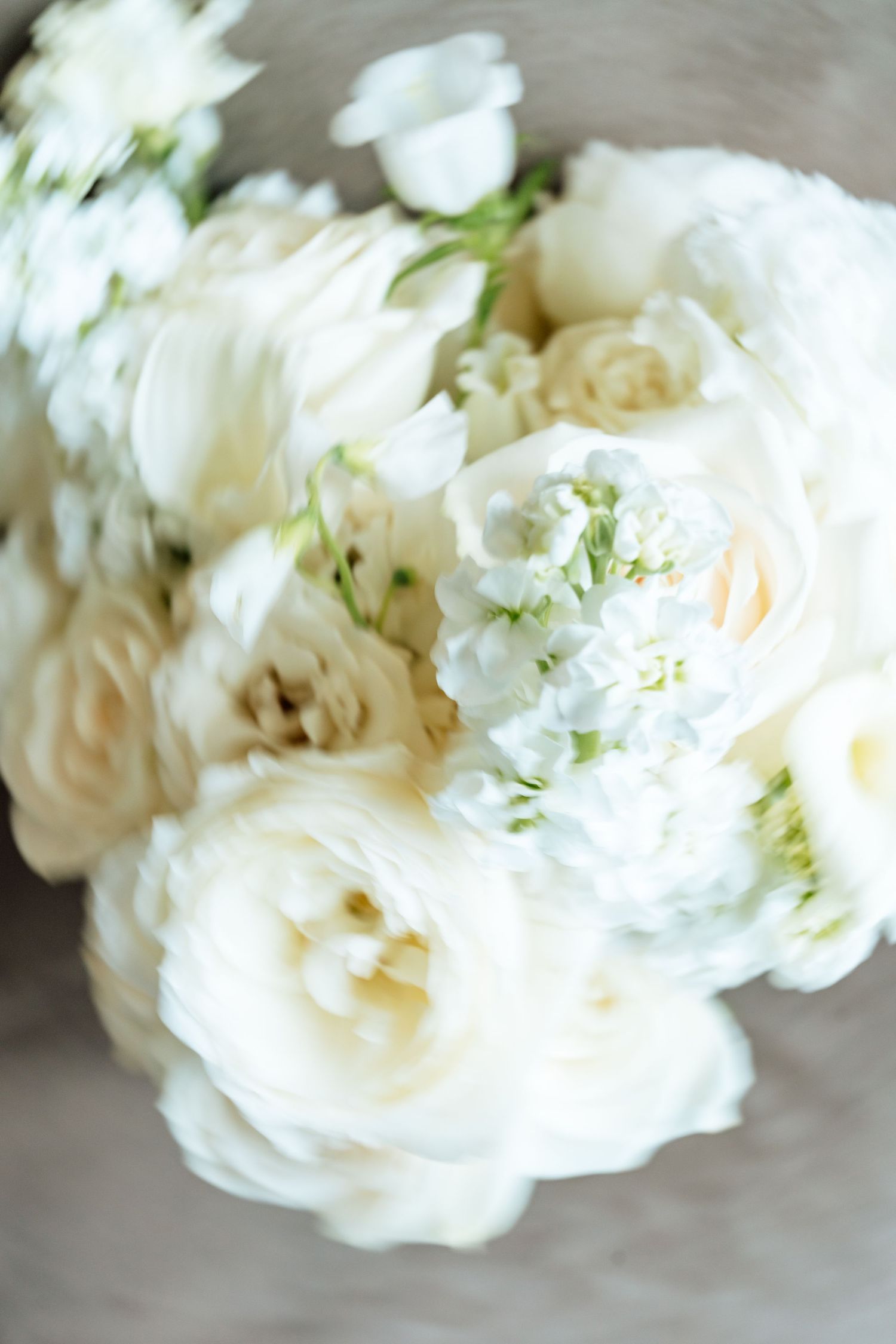 Dreamy soft white garden roses and peonies arranged in an ethereal wedding bouquet with delicate green accents.
