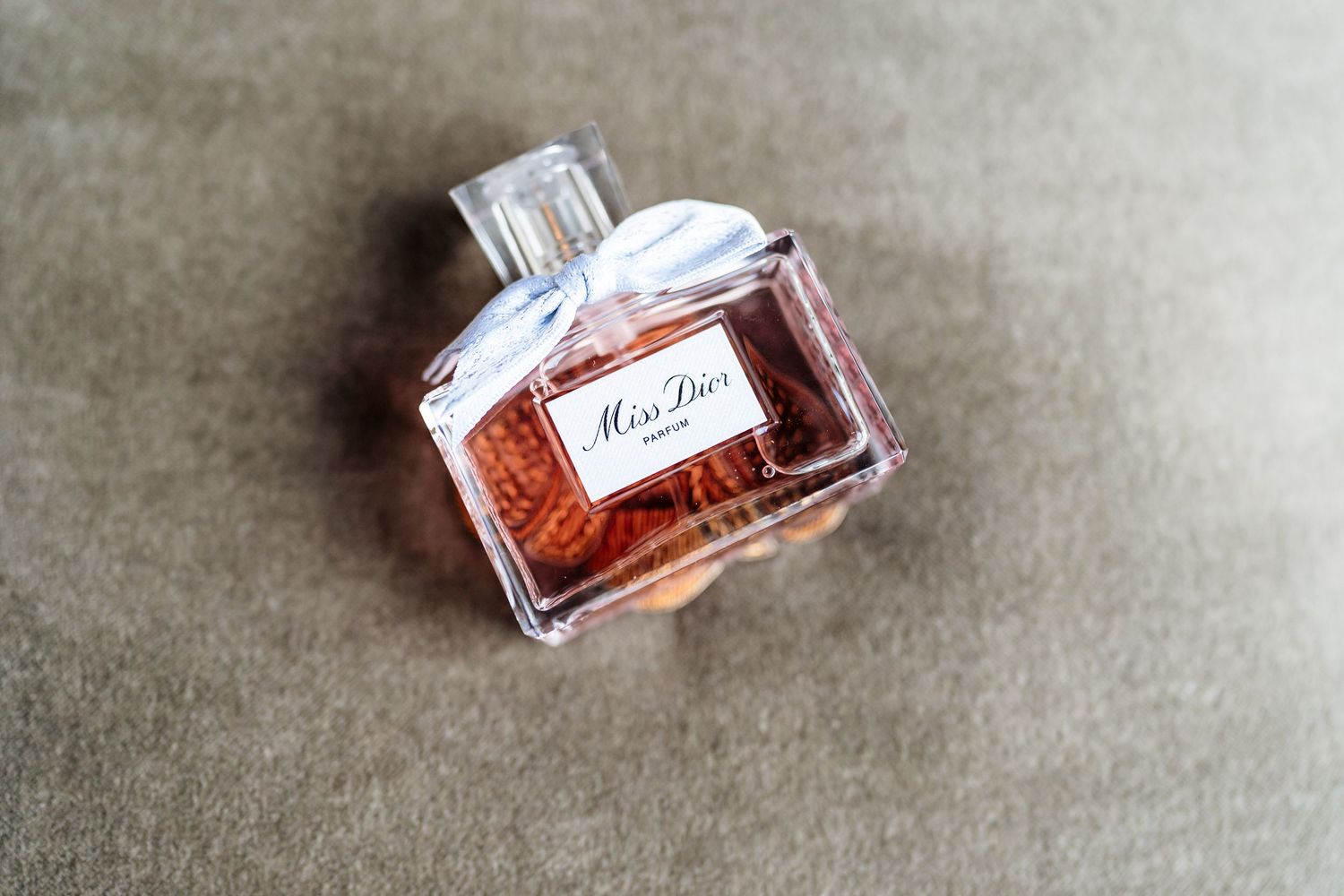 Six crystal perfume bottles with colorful fragrances arranged in a sequential row on a gray textured surface.