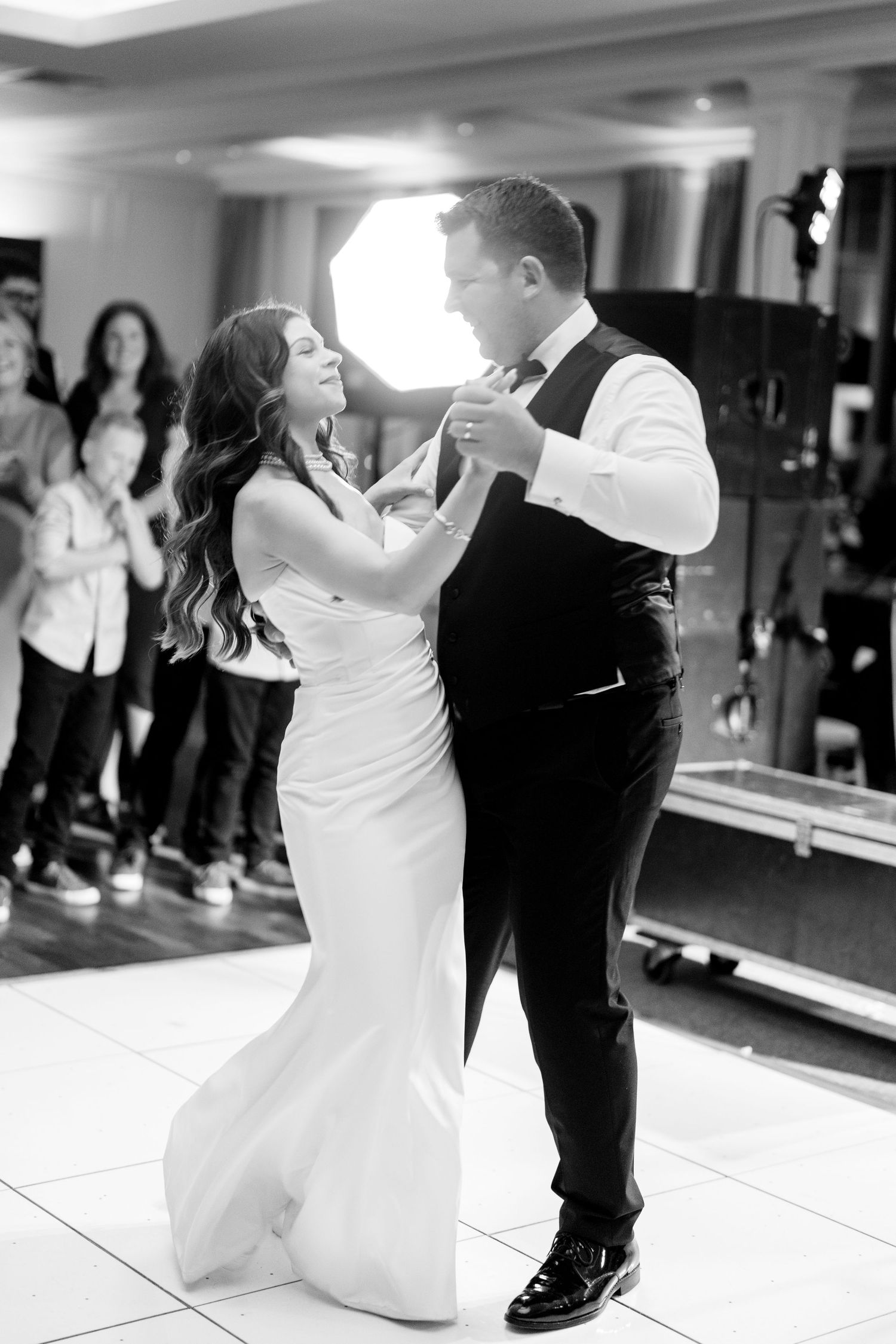 Bride and groom share their first dance together on an illuminated dance floor at their wedding reception.