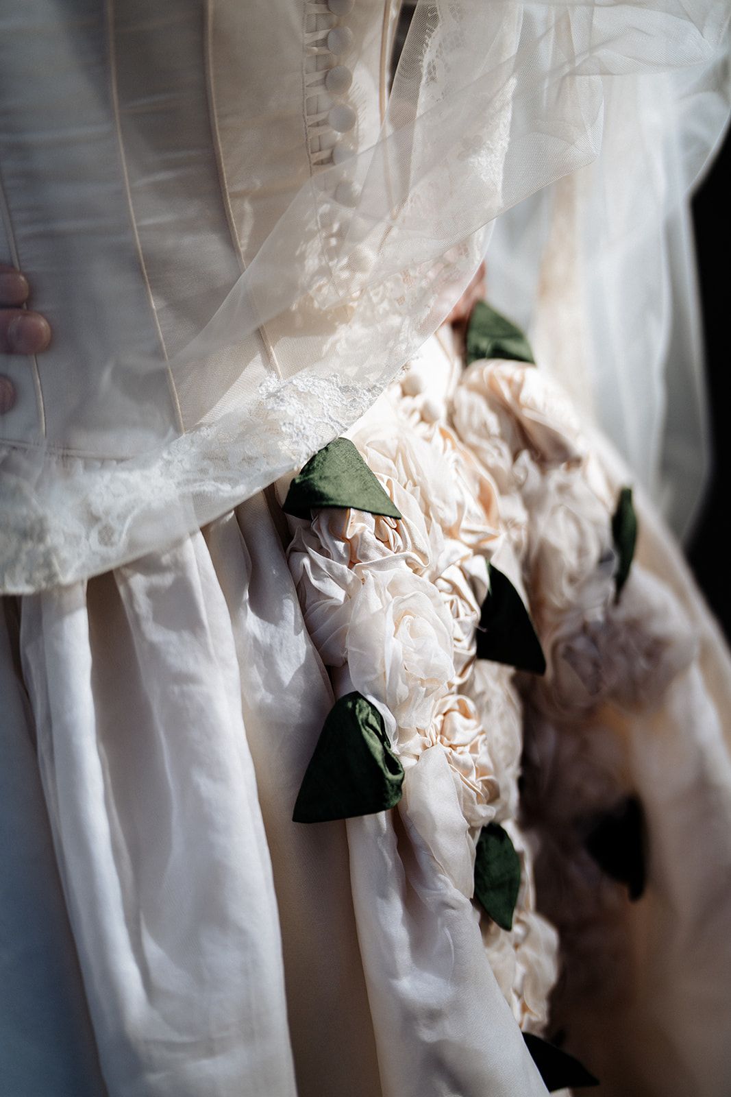 Close-up details of delicate white lace and fabric on wedding dresses hanging in a row.