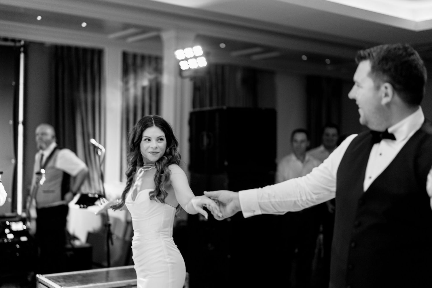 Group of wedding guests dancing and enjoying themselves on a crowded dance floor at an indoor reception.
