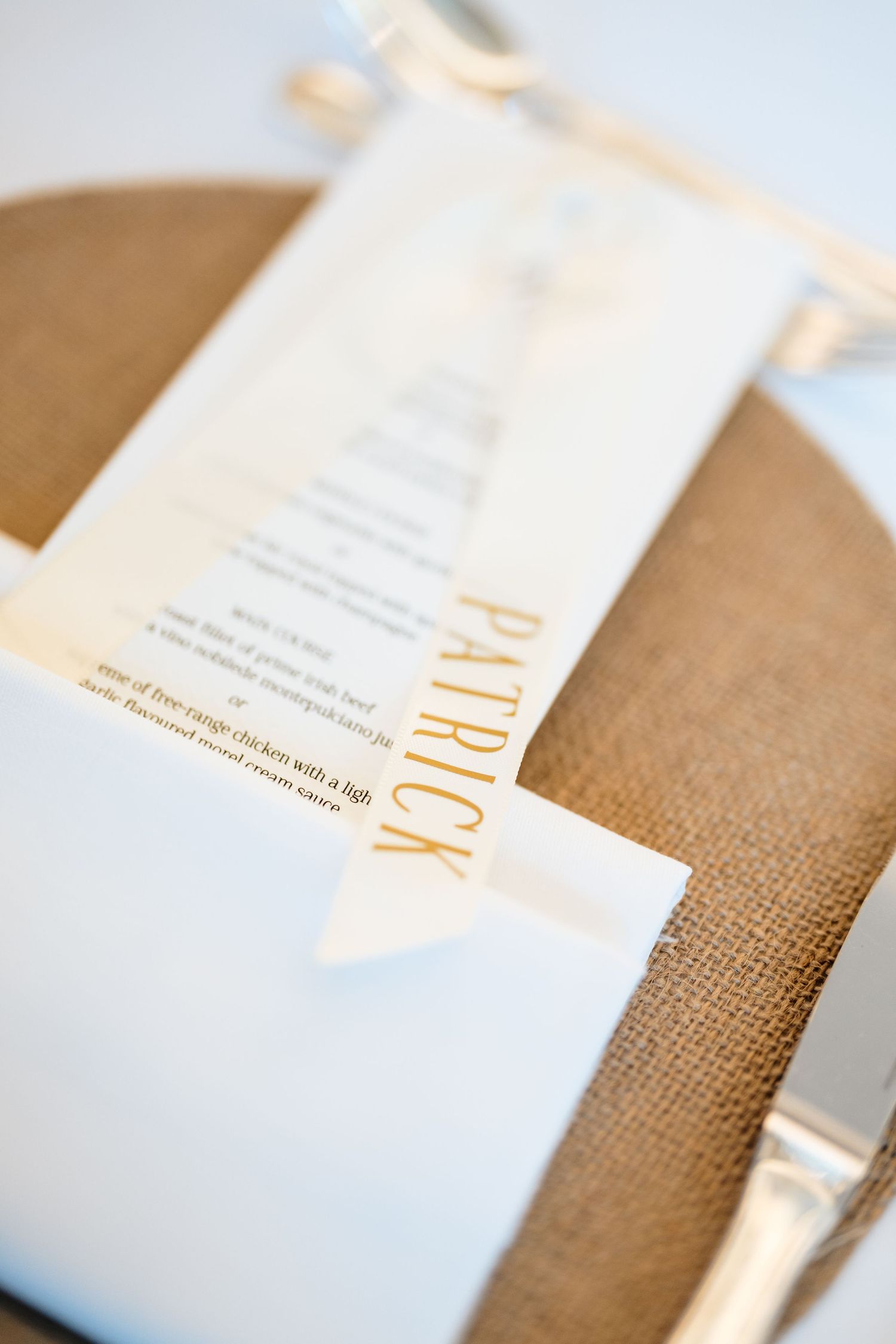 Close-up view of elegant white business cards with orange text on a textured burlap background.