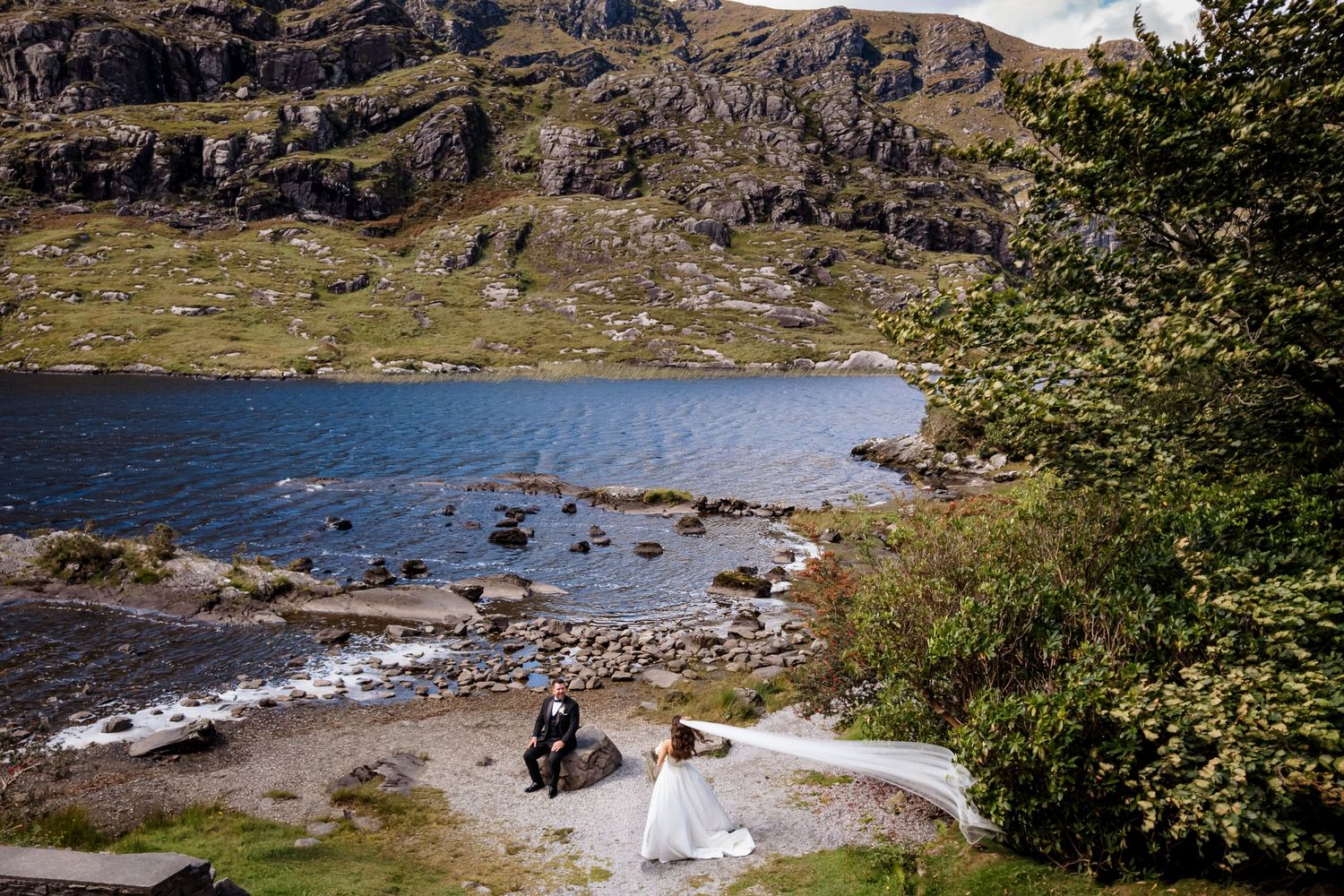 A panoramic view of rugged cliffs and a pristine lake surrounded by dramatic mountain landscape in remote wilderness.