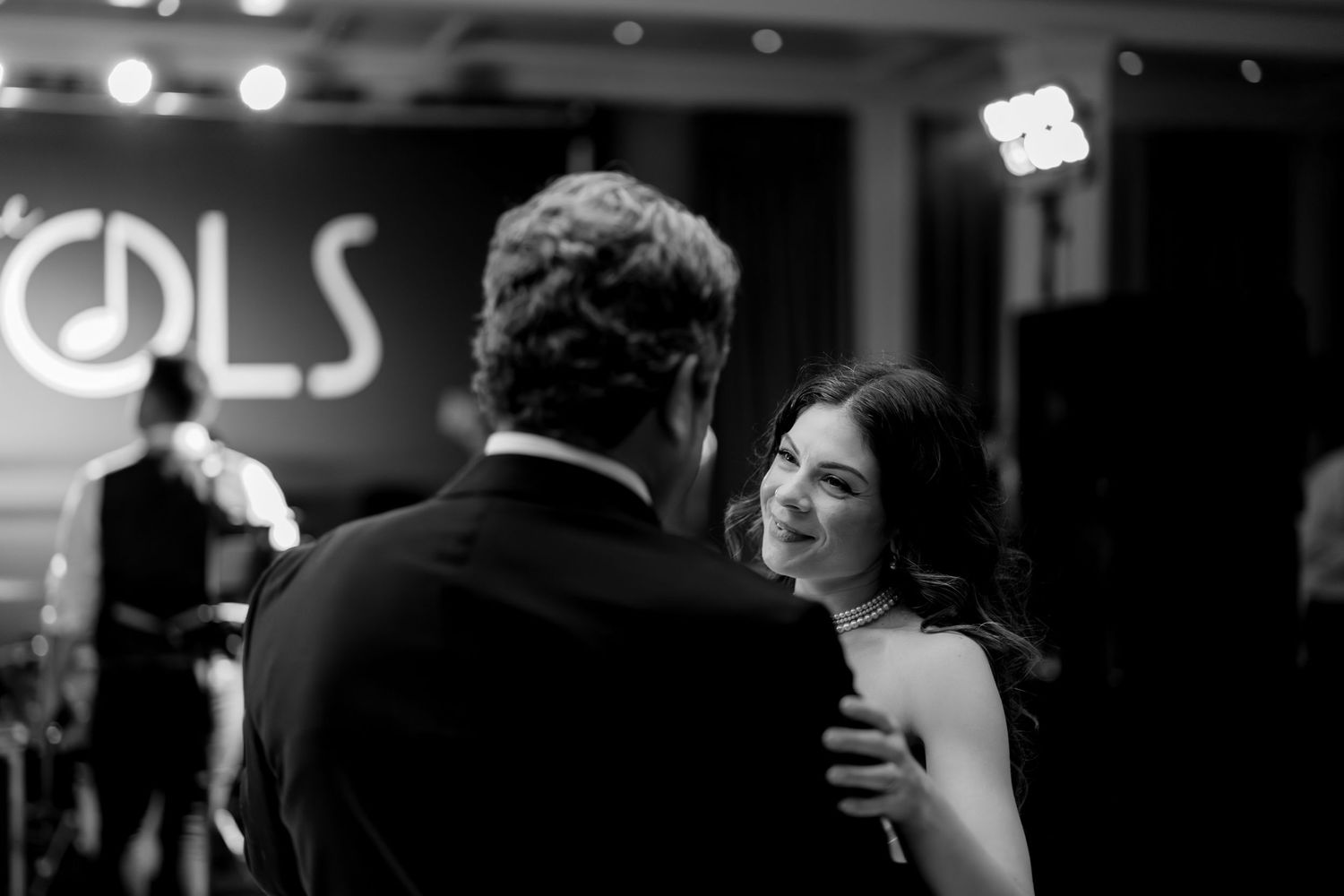 A series of black and white candid photos arranged in a filmstrip-style layout showing people dancing and socializing.