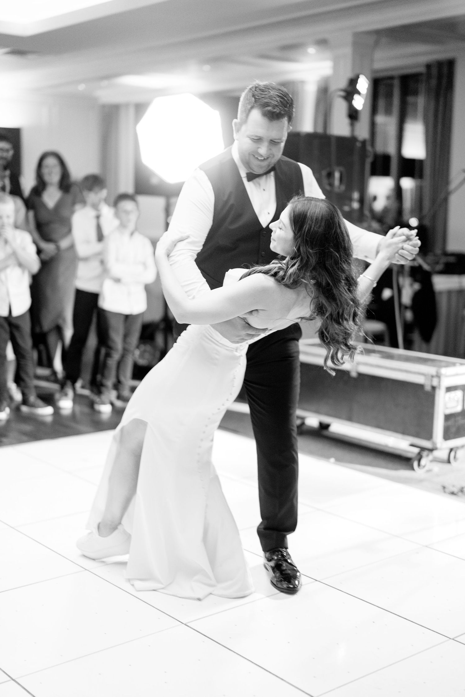 A black and white panoramic sequence showing a couple performing their first dance at a wedding reception.