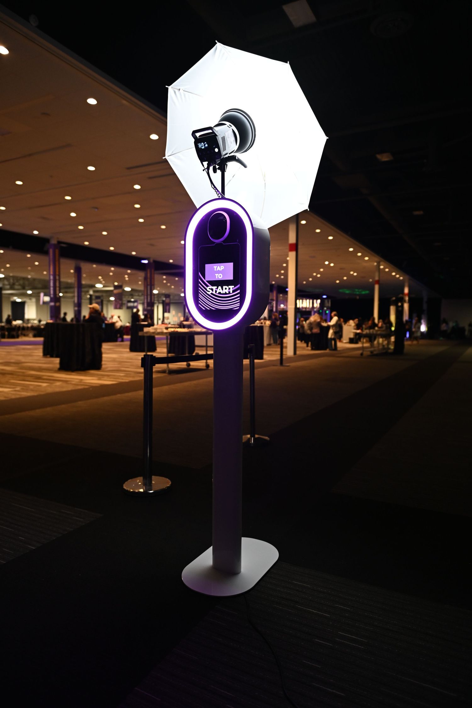 Purple illuminated Twitch streaming booth setup with professional lighting equipment in dark convention space.