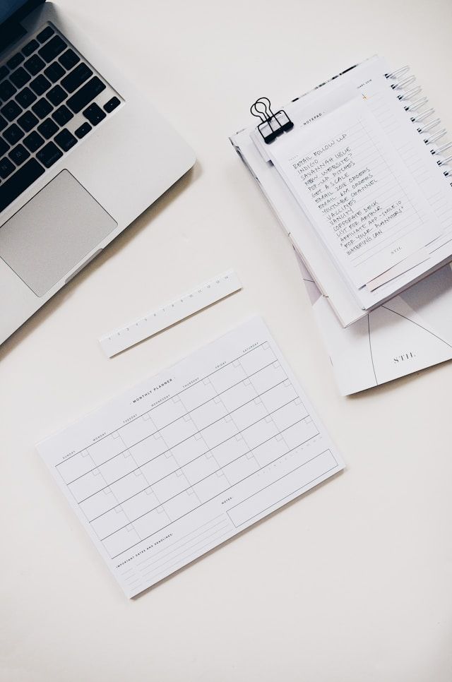 Minimalist workspace with laptop keyboard and blank paper documents arranged in a clean white setting.