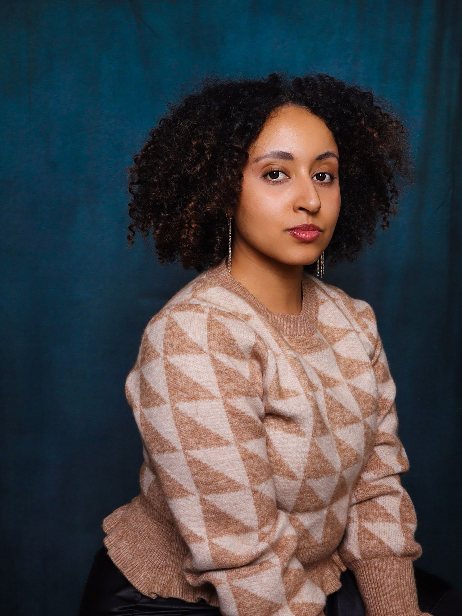 Portrait series showcasing a geometric patterned sweater against a deep blue background.