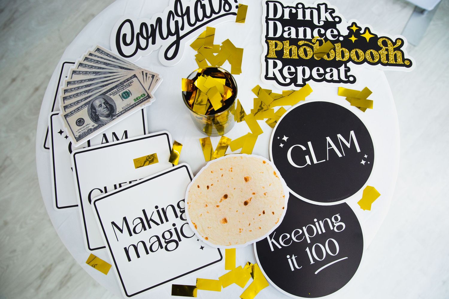 Collection of party-themed stickers and labels with gold confetti on marble surface.