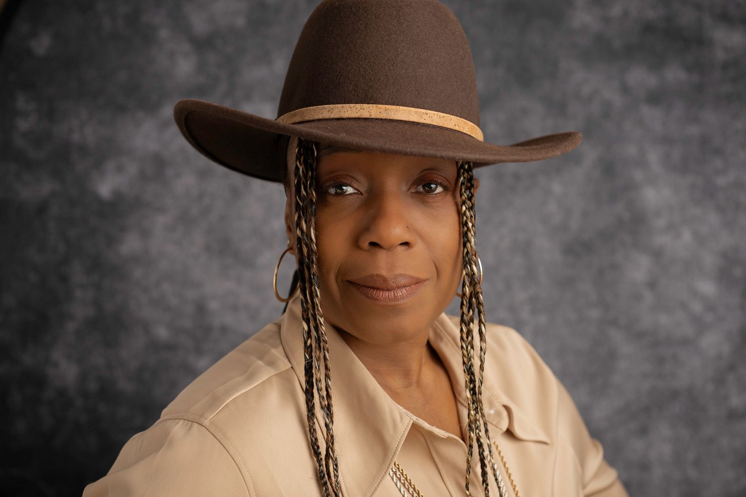 Portrait series featuring brown hat and beige outfit against grey backdrop.