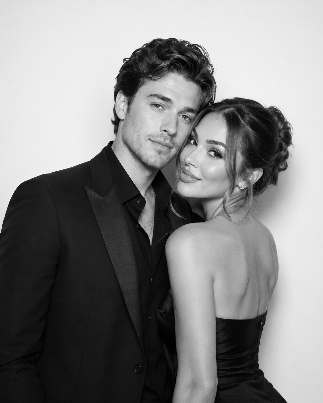 Black and white photo of an elegant couple posing together, man in suit and woman in strapless dress.
