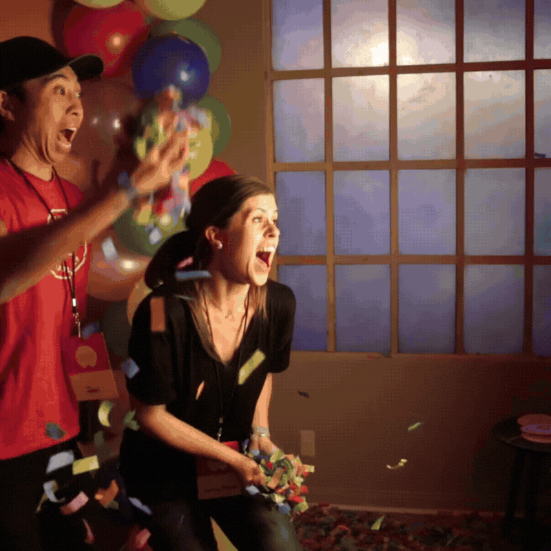 Attendees at a corporate event in toronto interacting with a led purple ring lit photo booth tapping the screen while throwing confetti