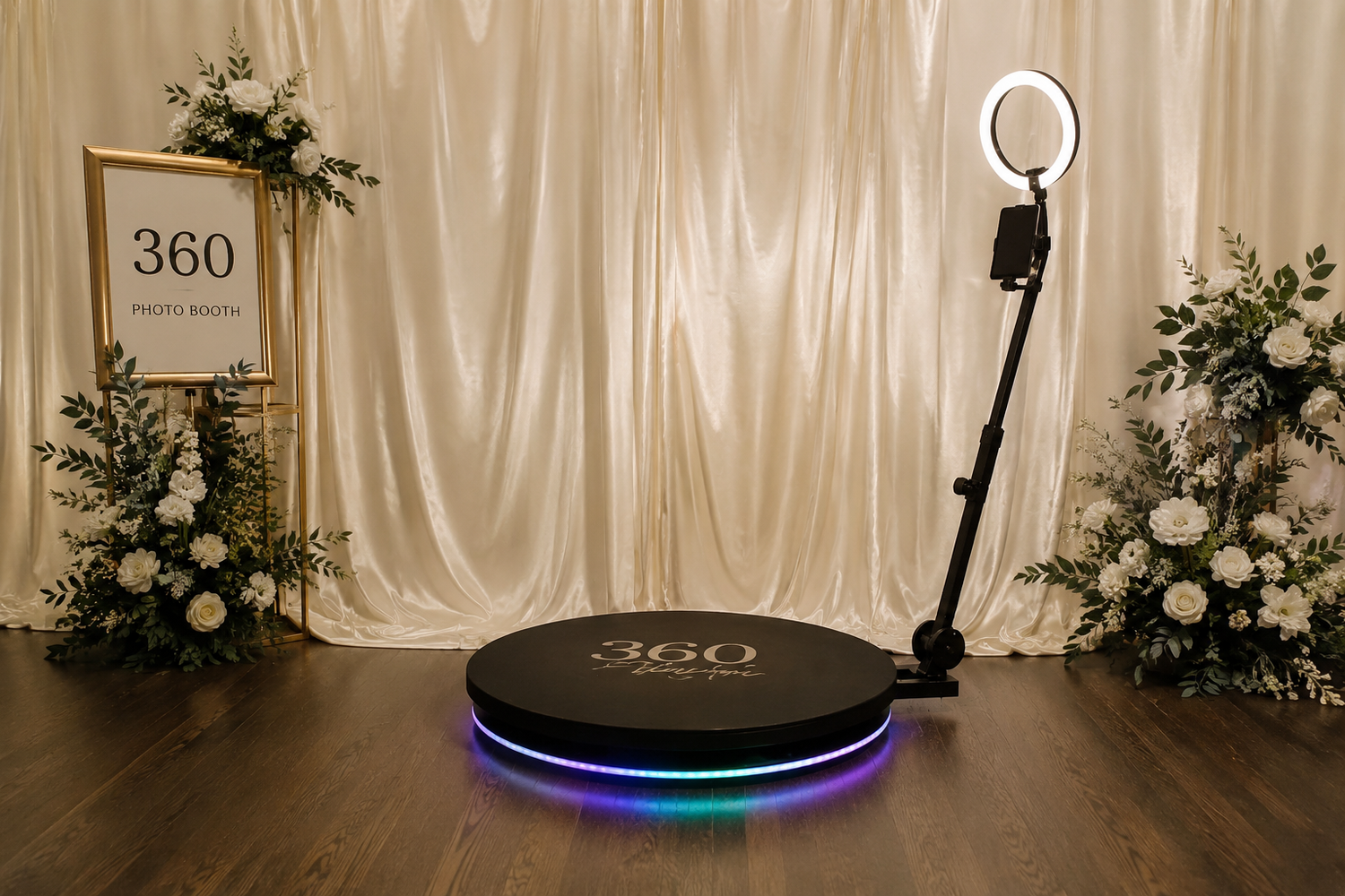 360 photo booth with RGB LED base, ring light, and floral arrangements against white drape backdrop.