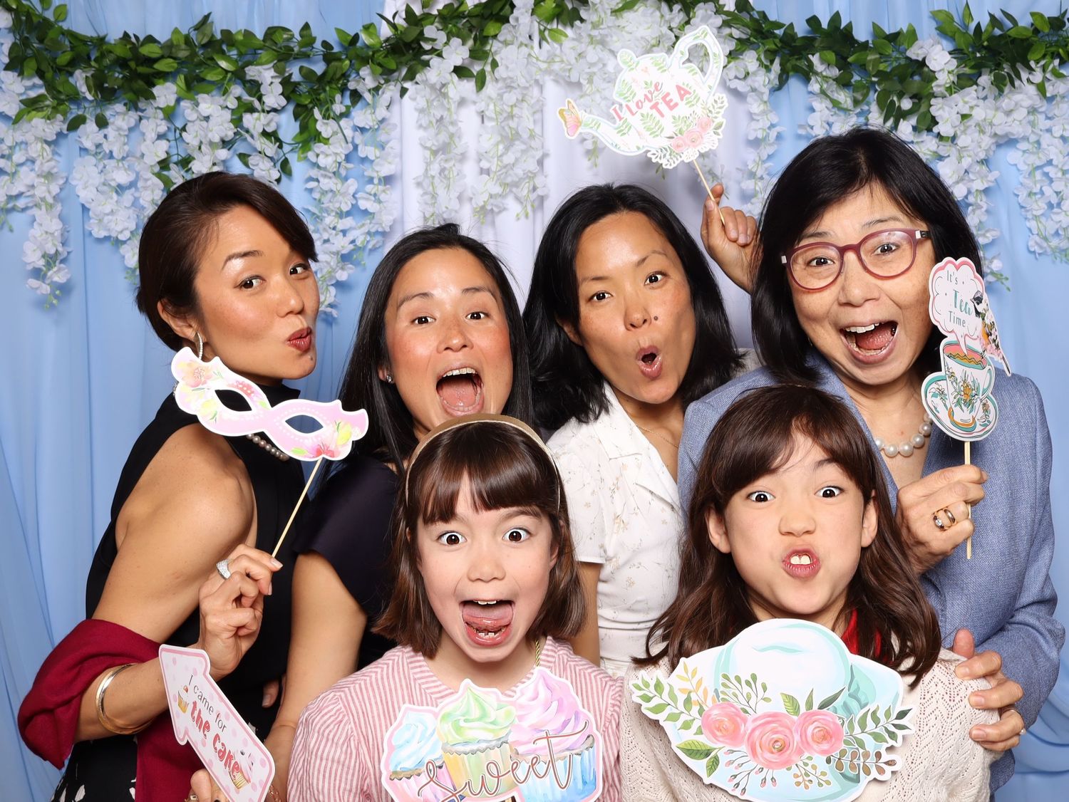 Photo booth strip showing people making fun expressions with floral decorations.