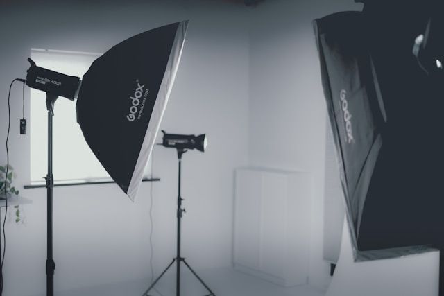 Professional photography studio setup with softboxes and lighting equipment against gray backdrop.