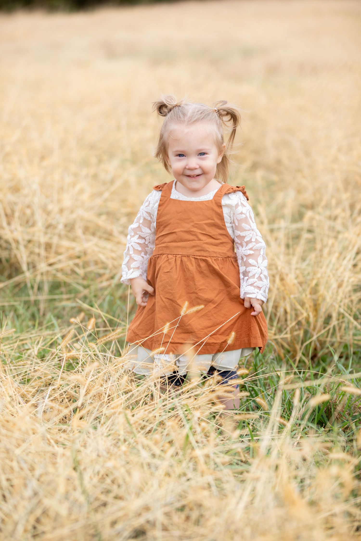 A young girl stands in a field of prairie grass.