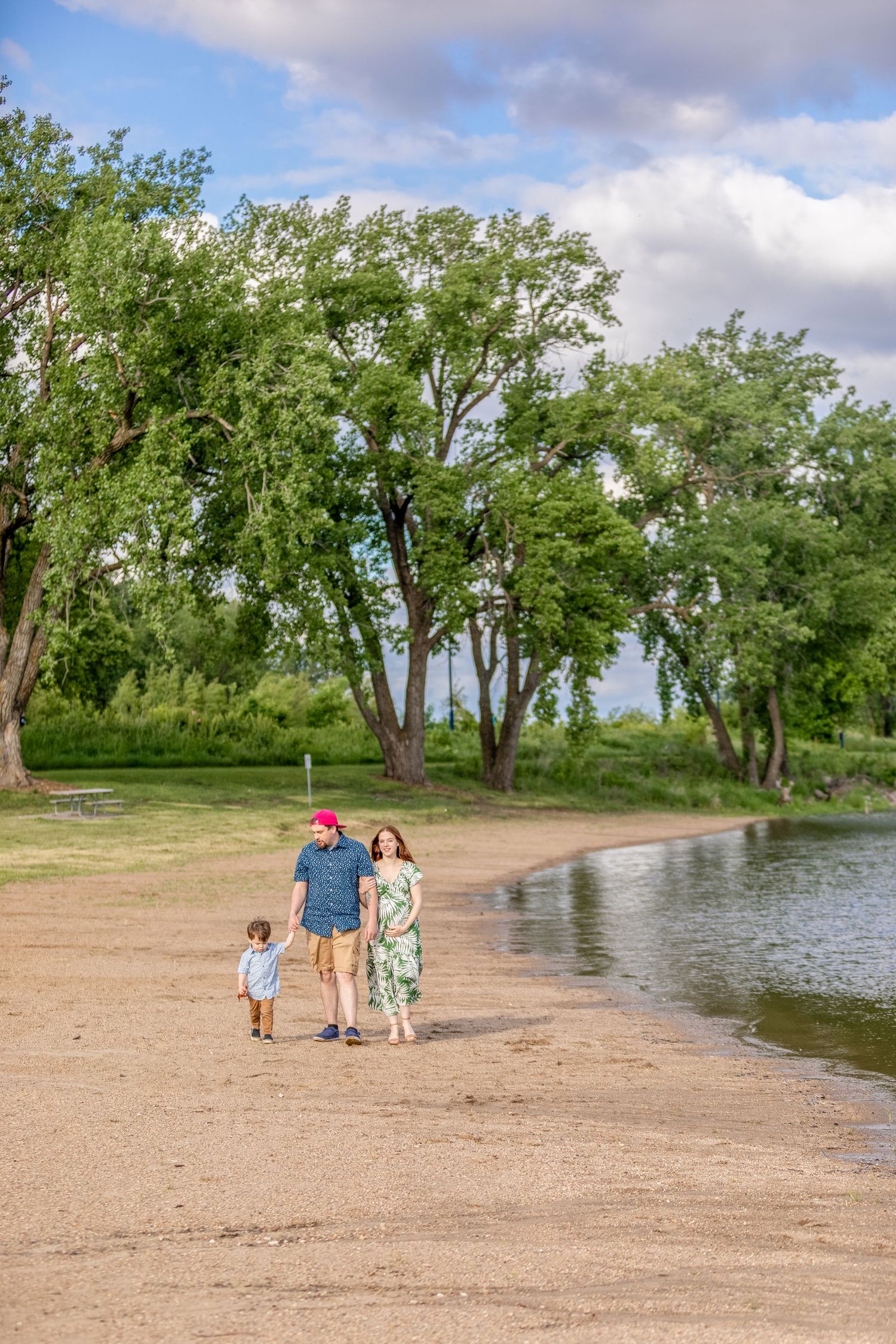 A joyful family walks along the lake at Gray's Lake Park in Des Moines, Iowa. on a sunny day.