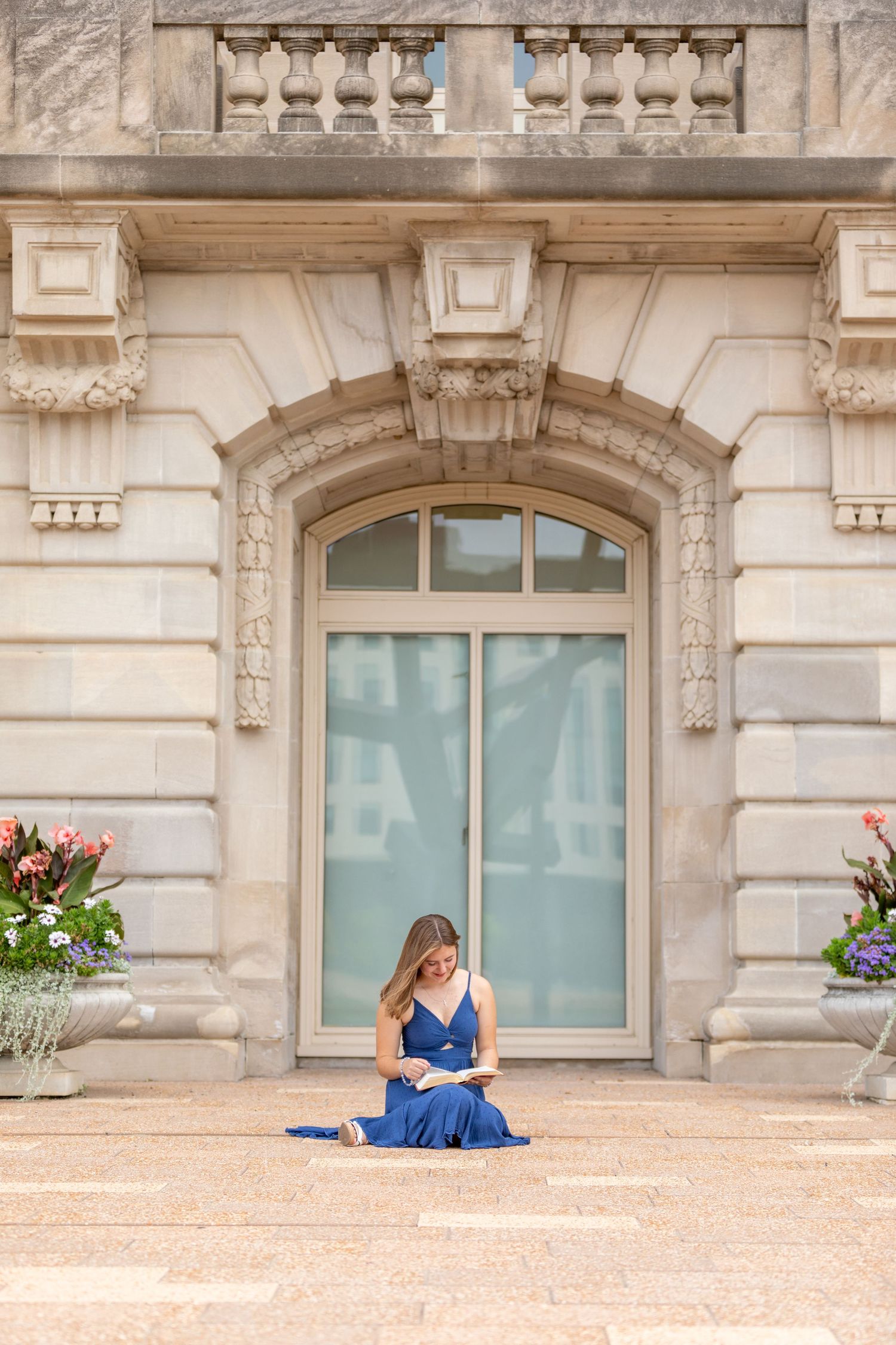 A high school senior reads her Bible in front of an ornate stone building in Des Moines, Iowa