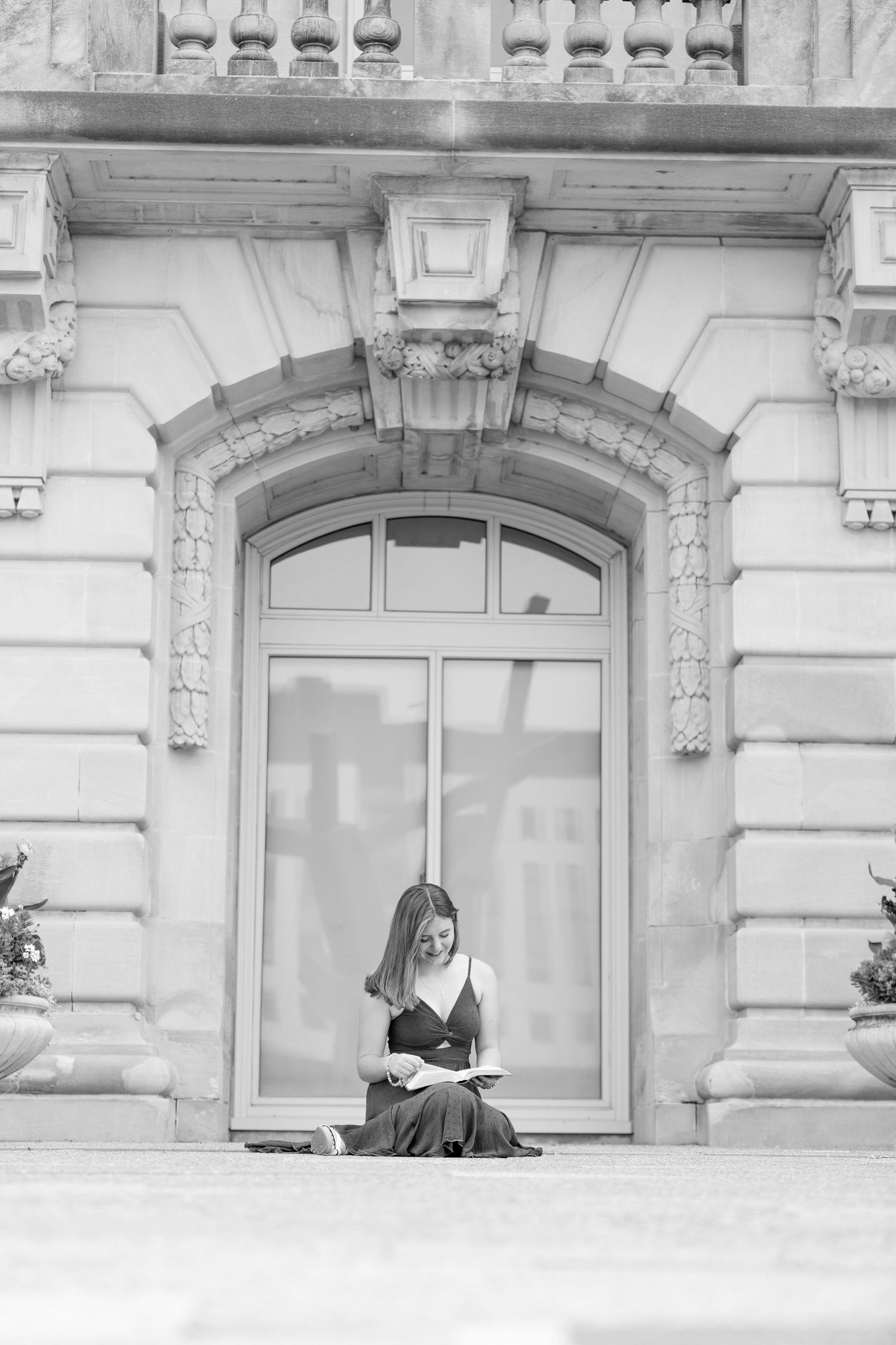 Black and white image of a high school senior reading her Bible, in front of an ornate stone building in Des Moines, Iowa