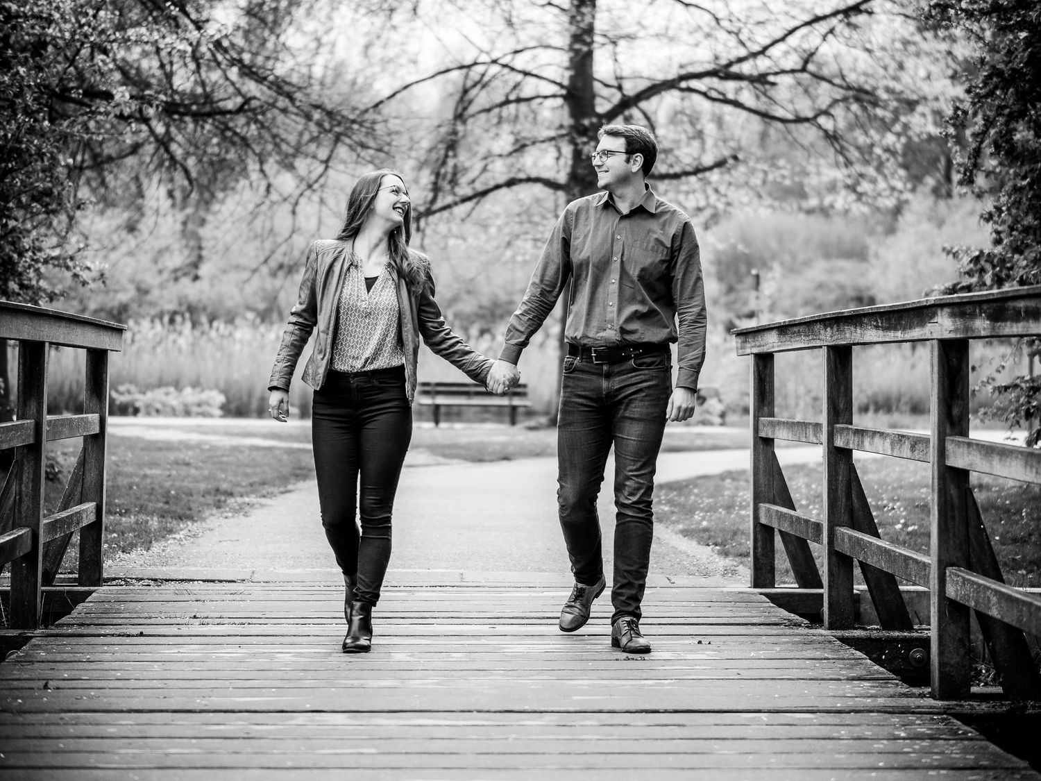 Black and white photo sequence showing two people walking hand in hand across a wooden bridge in a natural setting.