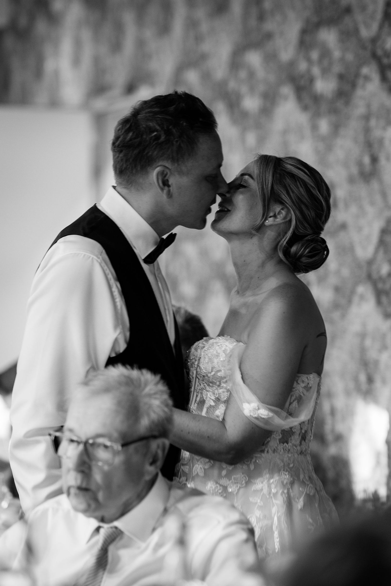 Bride and groom sharing an intimate moment nearly kissing at their wedding reception in black and white.